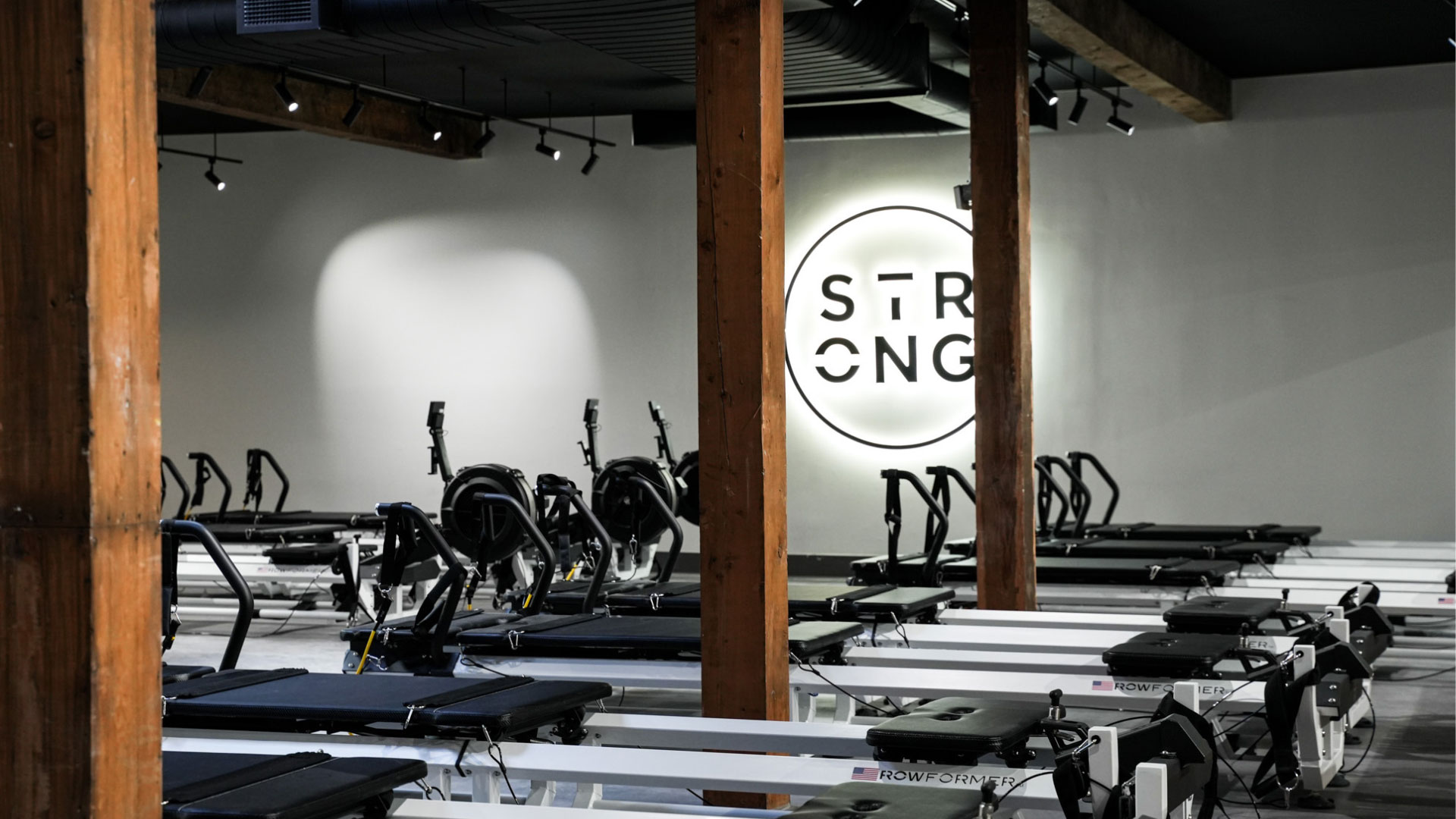 Studio STRONG Pilates z rzędami maszyn Rowformer i logo STRONG